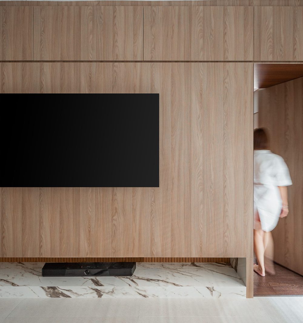 A concealed door blends seamlessly into the timber-panelled wall, opening through to the bedroom corridor beyond.