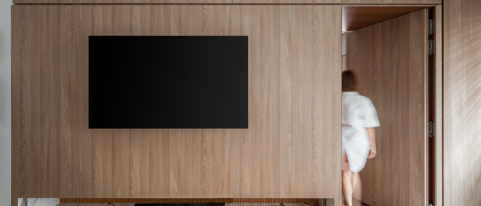 A concealed door blends seamlessly into the timber-panelled wall, opening through to the bedroom corridor beyond.