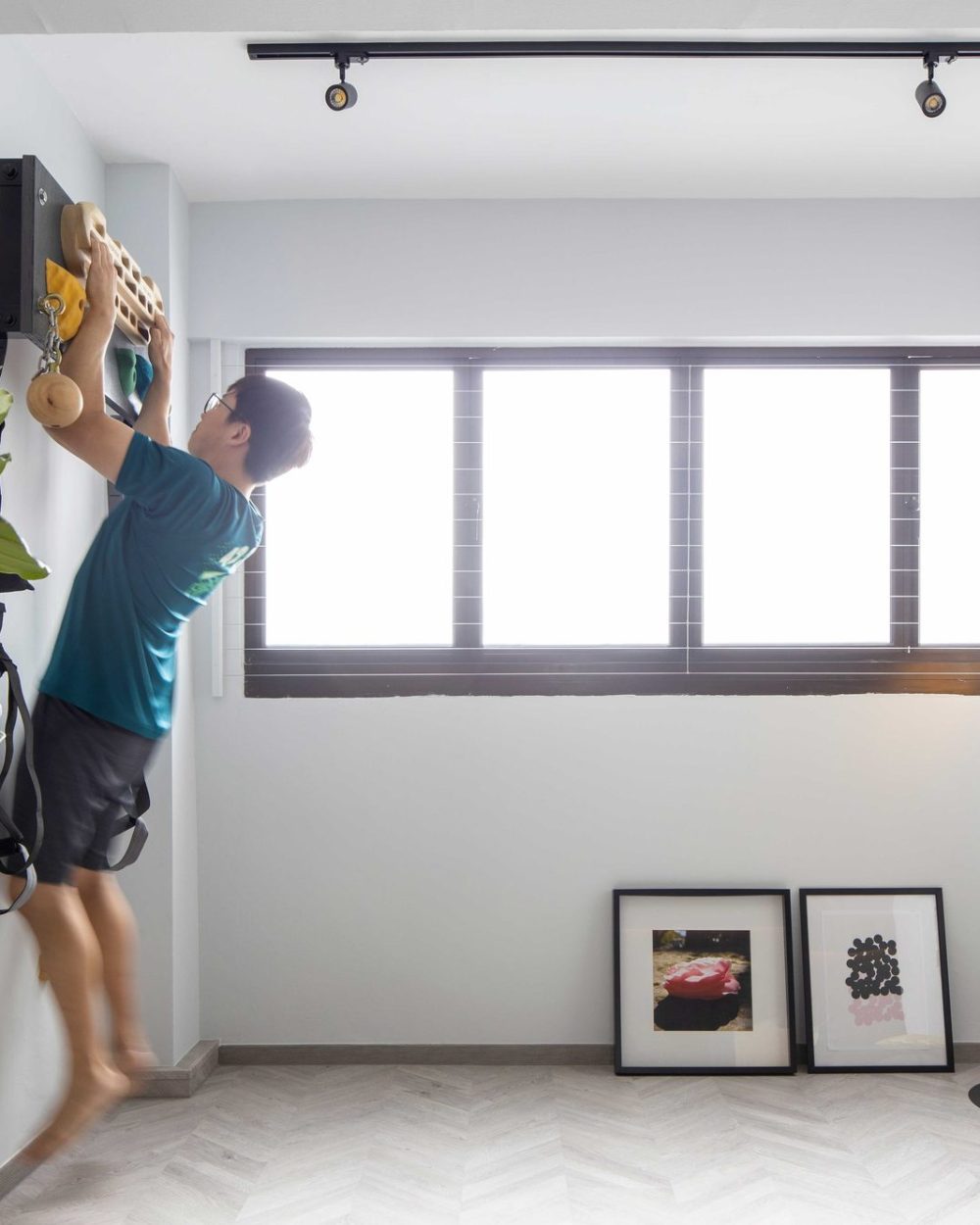 A bouldering hold and resistance bands turn this corner into a compact home gym, lit by natural light from louvred windows.