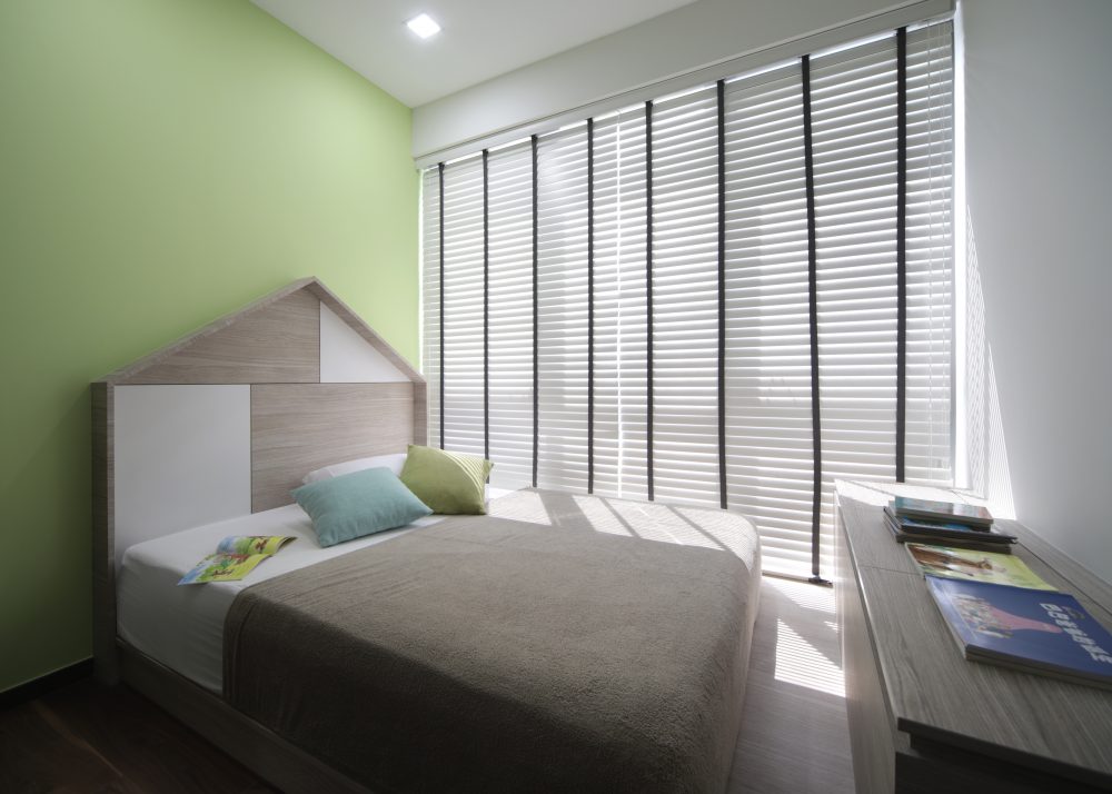 A house-shaped timber headboard gives the children's room a playful focal point, set against a fresh green accent wall.