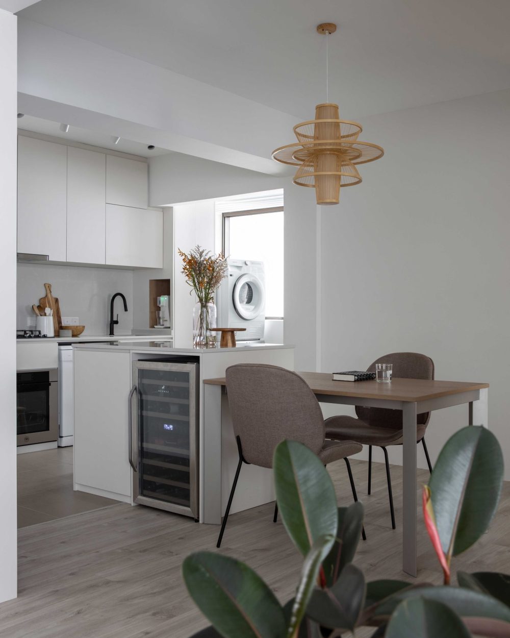 A built-in wine chiller sits within the kitchen island, positioned beside a dining nook that looks out toward the laundry area.