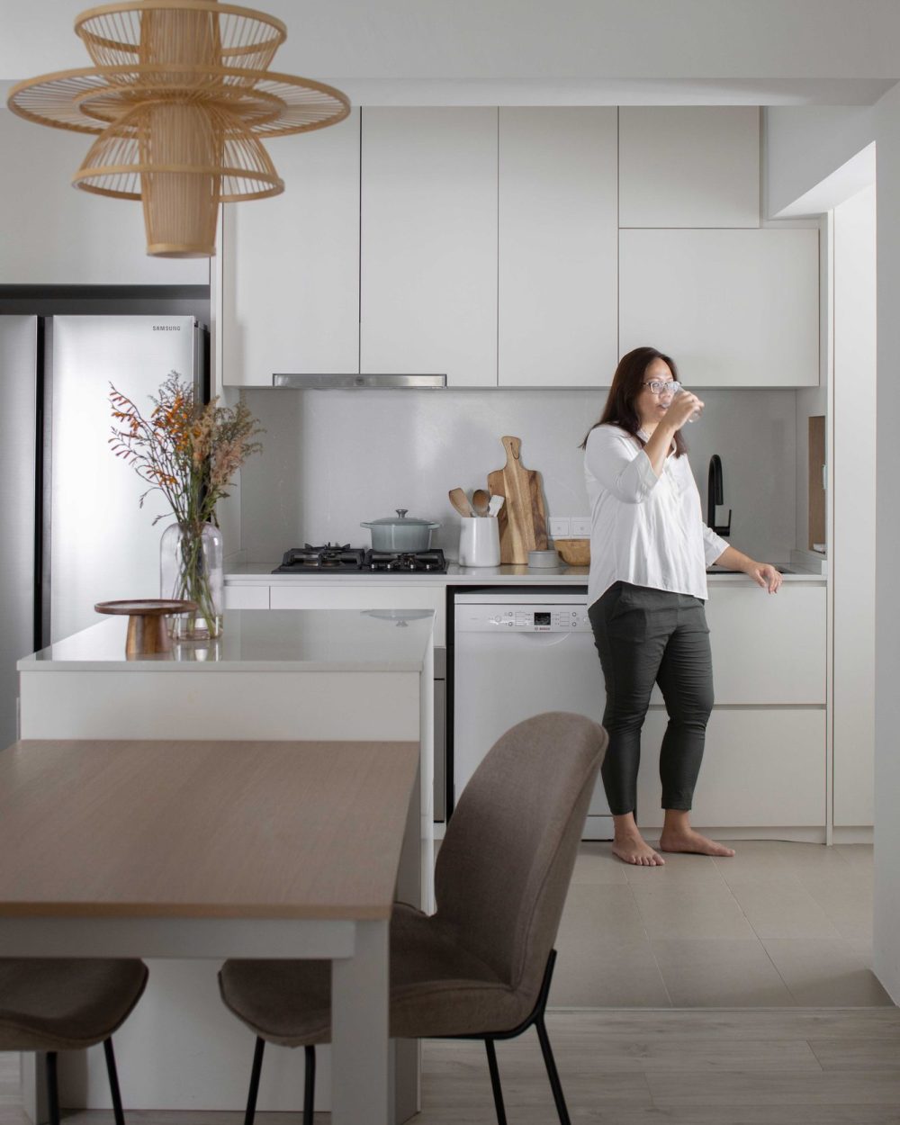 The finished kitchen in everyday use, with the homeowner enjoying a quiet moment by the sink.