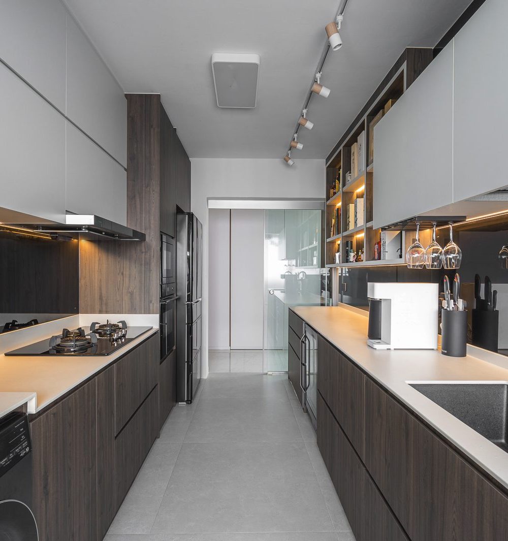 A generous galley kitchen runs the length of the unit, with a black glass splashback, built-in oven column and glass-panelled entrance.