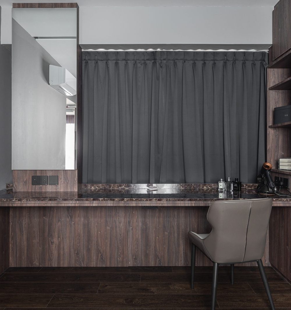 A dark marble-topped dressing table sits beneath blackout curtains, paired with a full-length mirror and a leather chair.