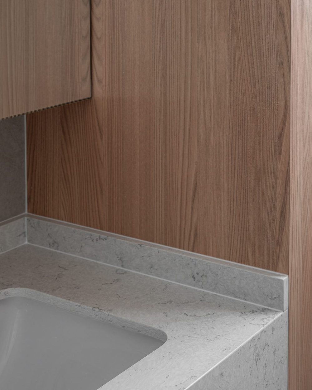 A closer look at the vanity's veined marble edge and undermount sink, set against the timber wall behind.
