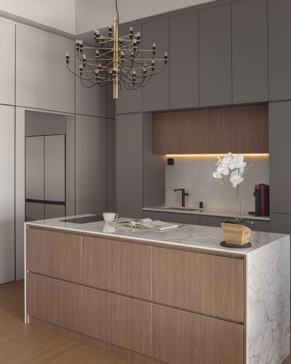 A marble waterfall-edge island holds the kitchen's sink and workspace, finished with matte black tapware and a built-in coffee station.