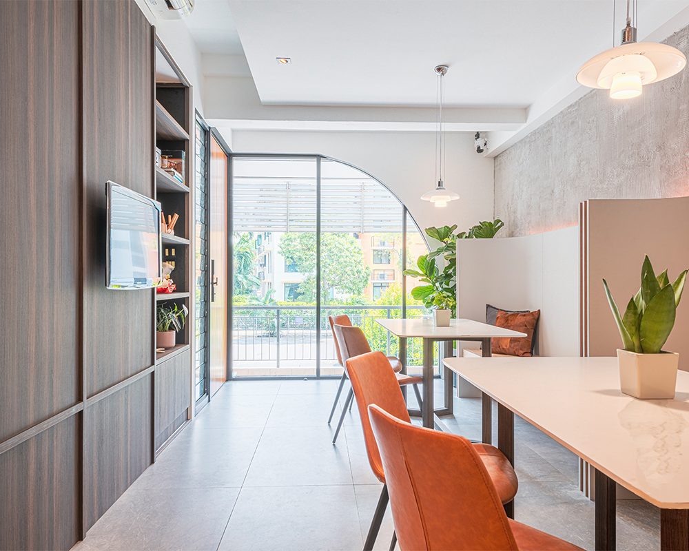 Burnt orange leather chairs and a curved banquette seat furnish a meeting corner, set beneath an arched window that echoes the entrance.