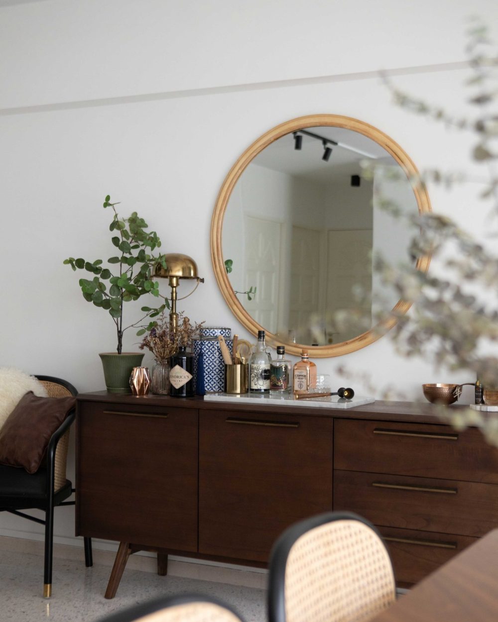 The full walnut sideboard doubles as a bar and display surface, its brass hardware echoing the kitchen's fittings.