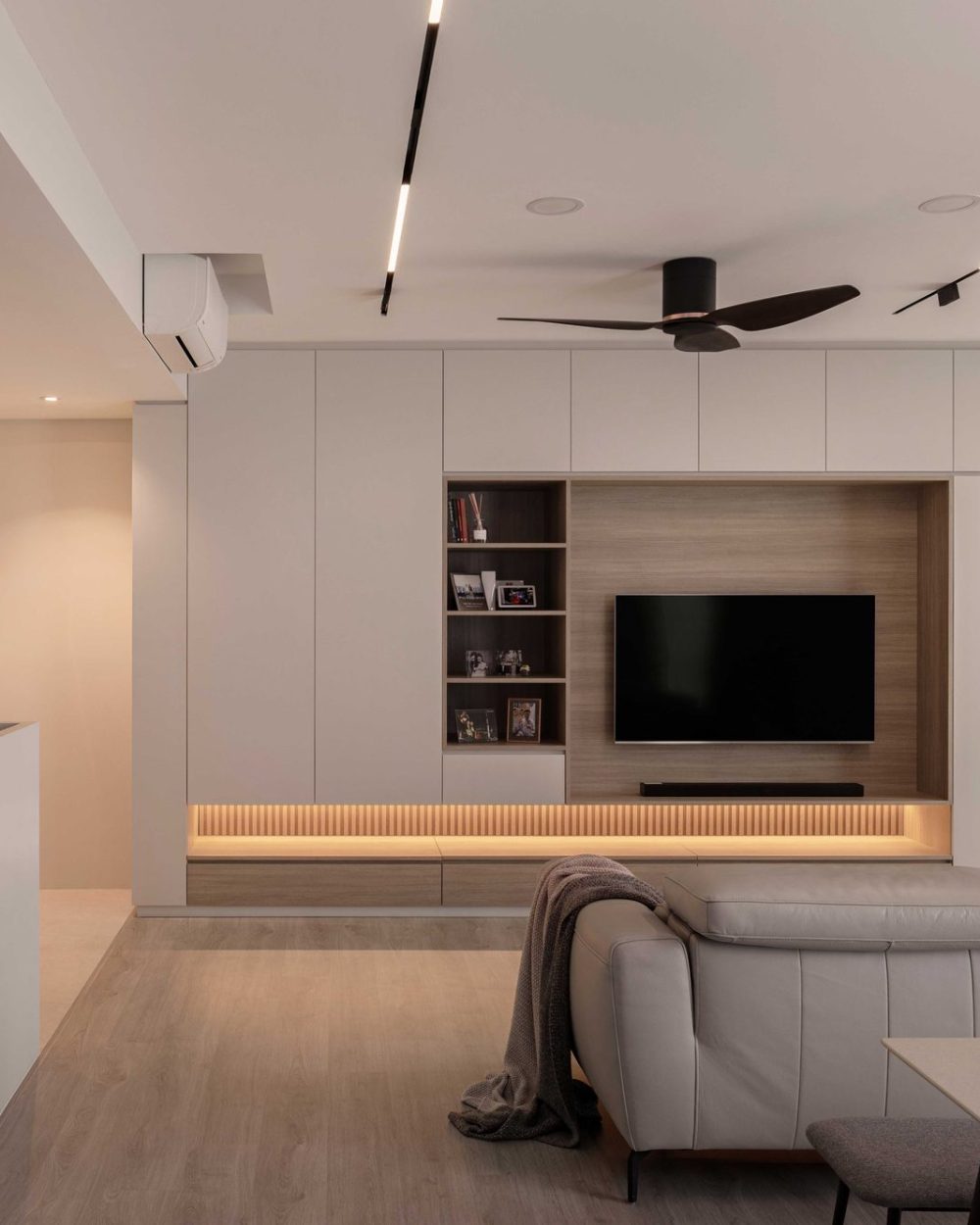 Full-height white cabinetry wraps a warm timber TV niche, finished with open shelving for books and framed photos.