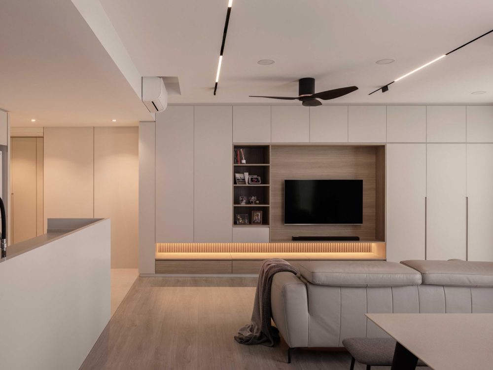 Full-height white cabinetry wraps a warm timber TV niche, finished with open shelving for books and framed photos.