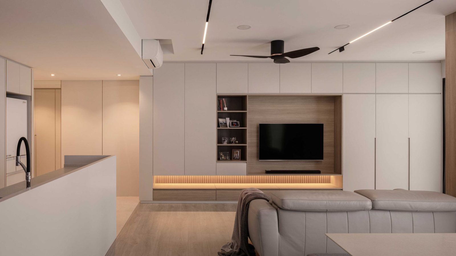 Full-height white cabinetry wraps a warm timber TV niche, finished with open shelving for books and framed photos.