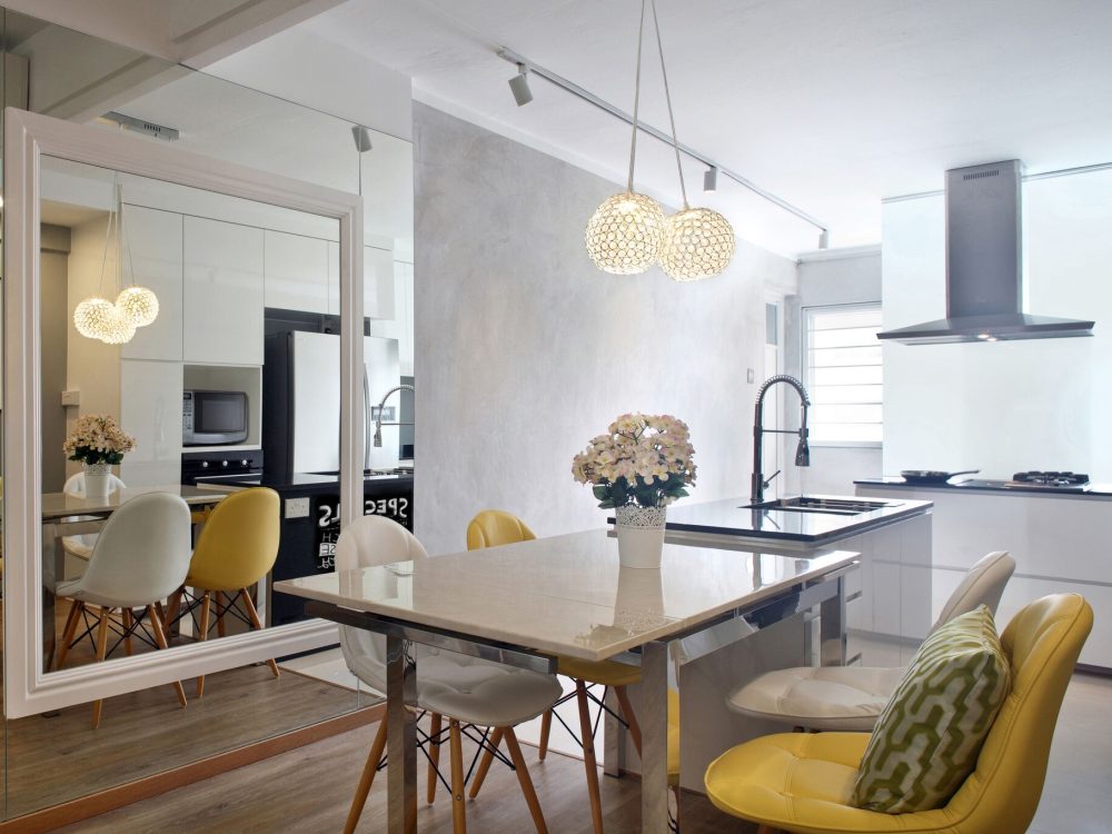 Crystal ball pendants hang over a marble-topped dining table, with a full-height mirror wall visually doubling the open kitchen beyond.
