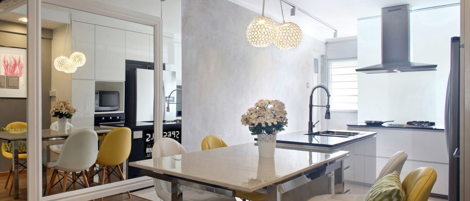 Crystal ball pendants hang over a marble-topped dining table, with a full-height mirror wall visually doubling the open kitchen beyond.