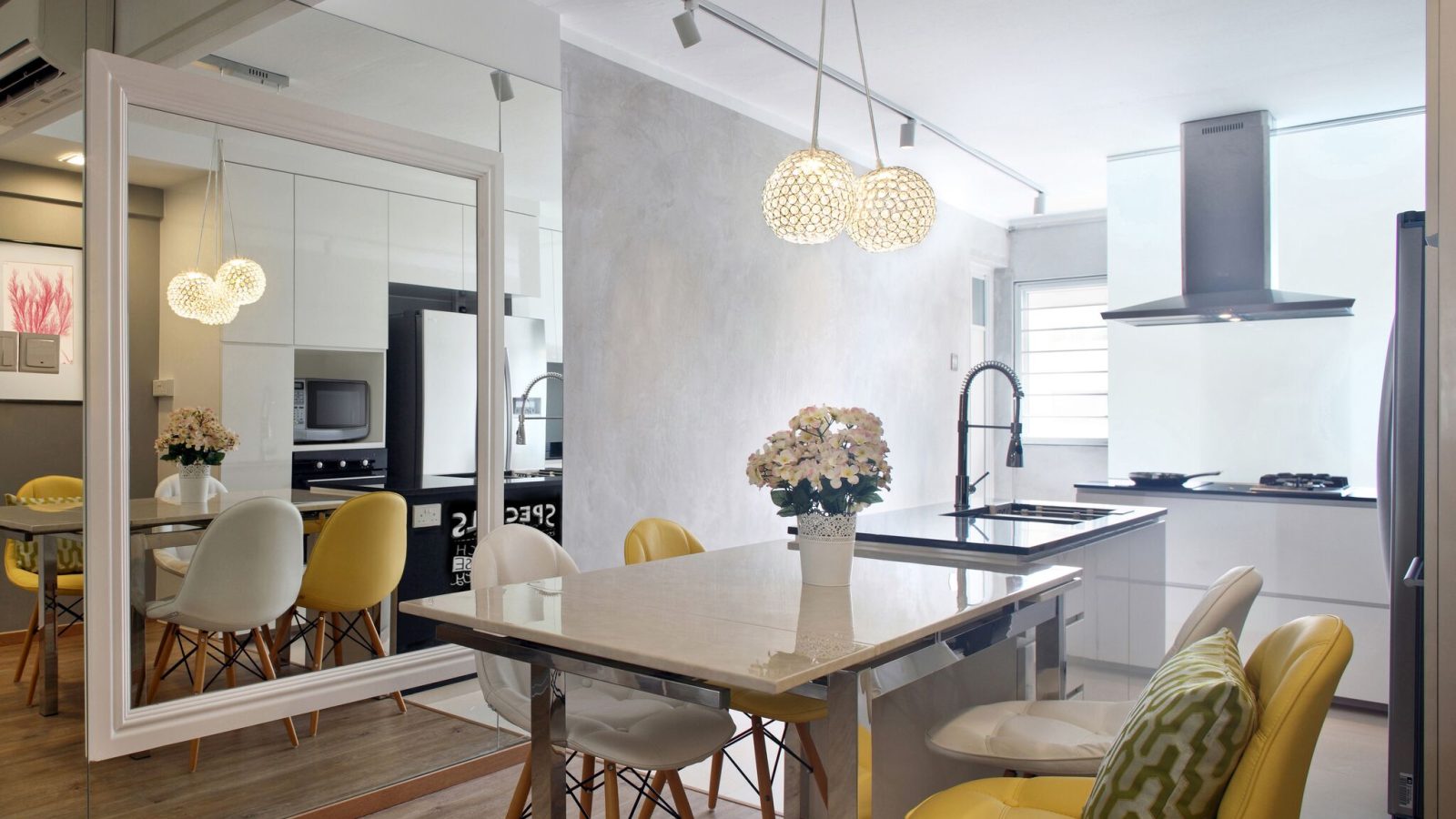Crystal ball pendants hang over a marble-topped dining table, with a full-height mirror wall visually doubling the open kitchen beyond.