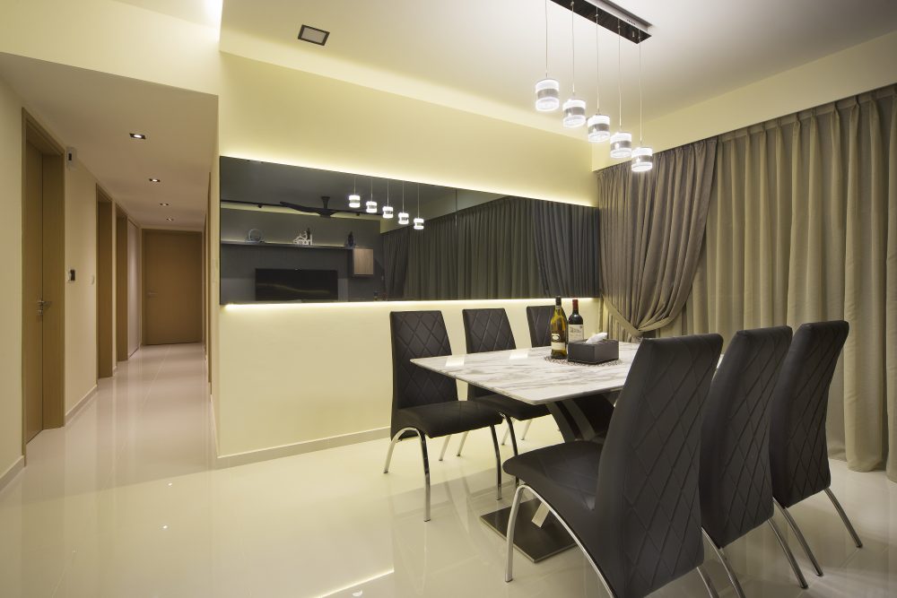 A mirrored feature wall doubles the sense of space in the dining area, reflecting the kitchen and a cluster of pendant lights overhead.