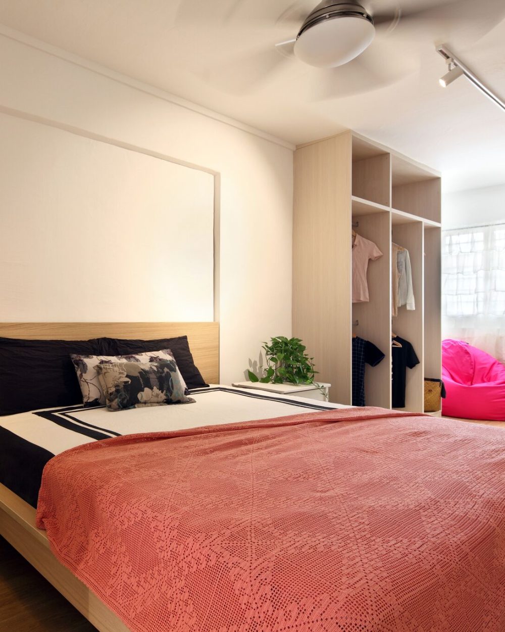 Black-and-white bedding and a warm wood headboard wall anchor the master bedroom, with open wardrobe shelving and a glimpse of the ensuite bathroom.