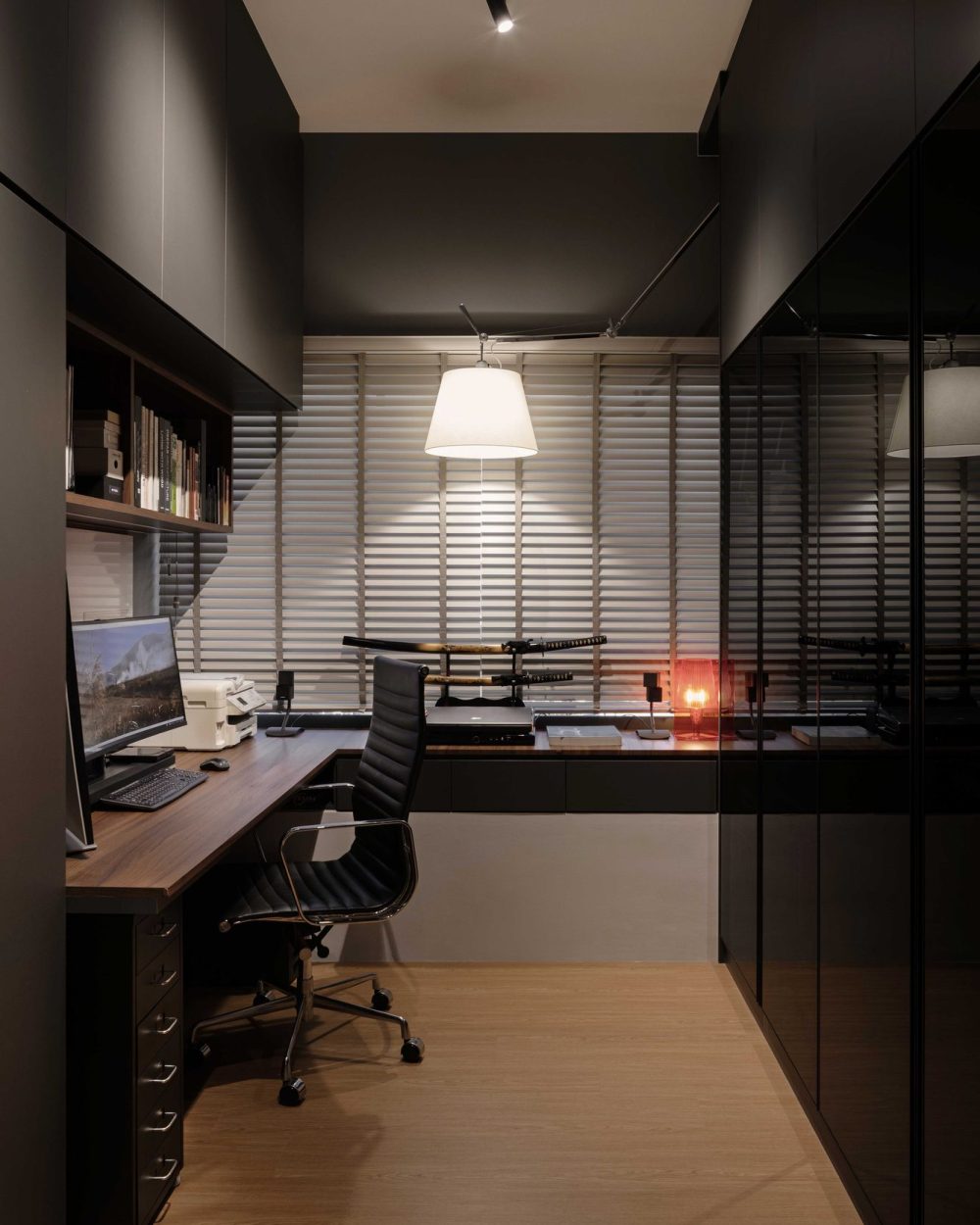 Matte black cabinetry and striped blinds set a focused tone in the home office, personalised with a displayed pair of samurai swords.
