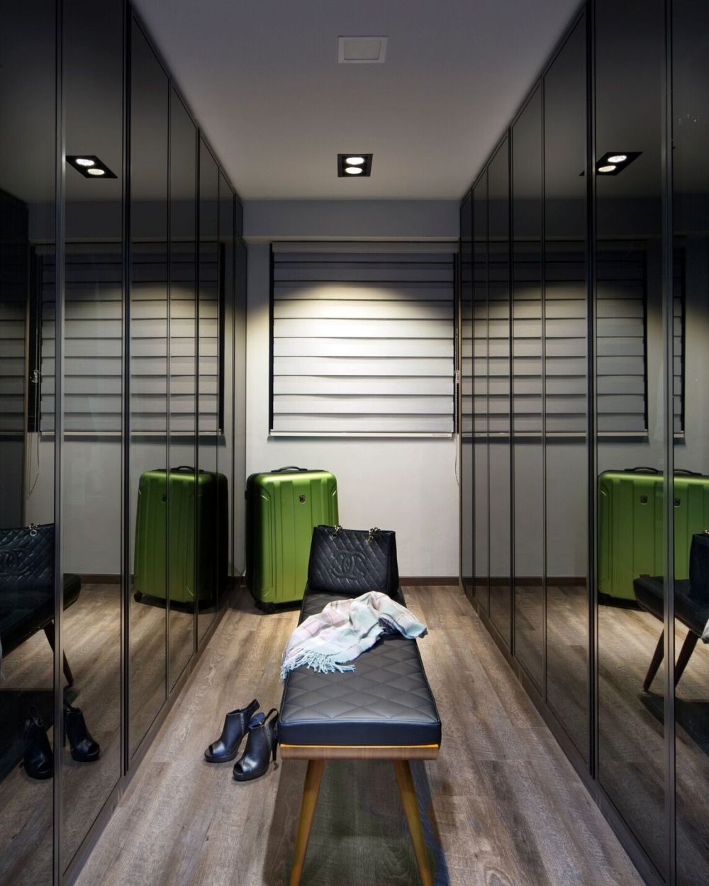 Sliding smoked glass doors reveal neatly hung clothing and drawers within, keeping the wardrobe both organised and visually contained.