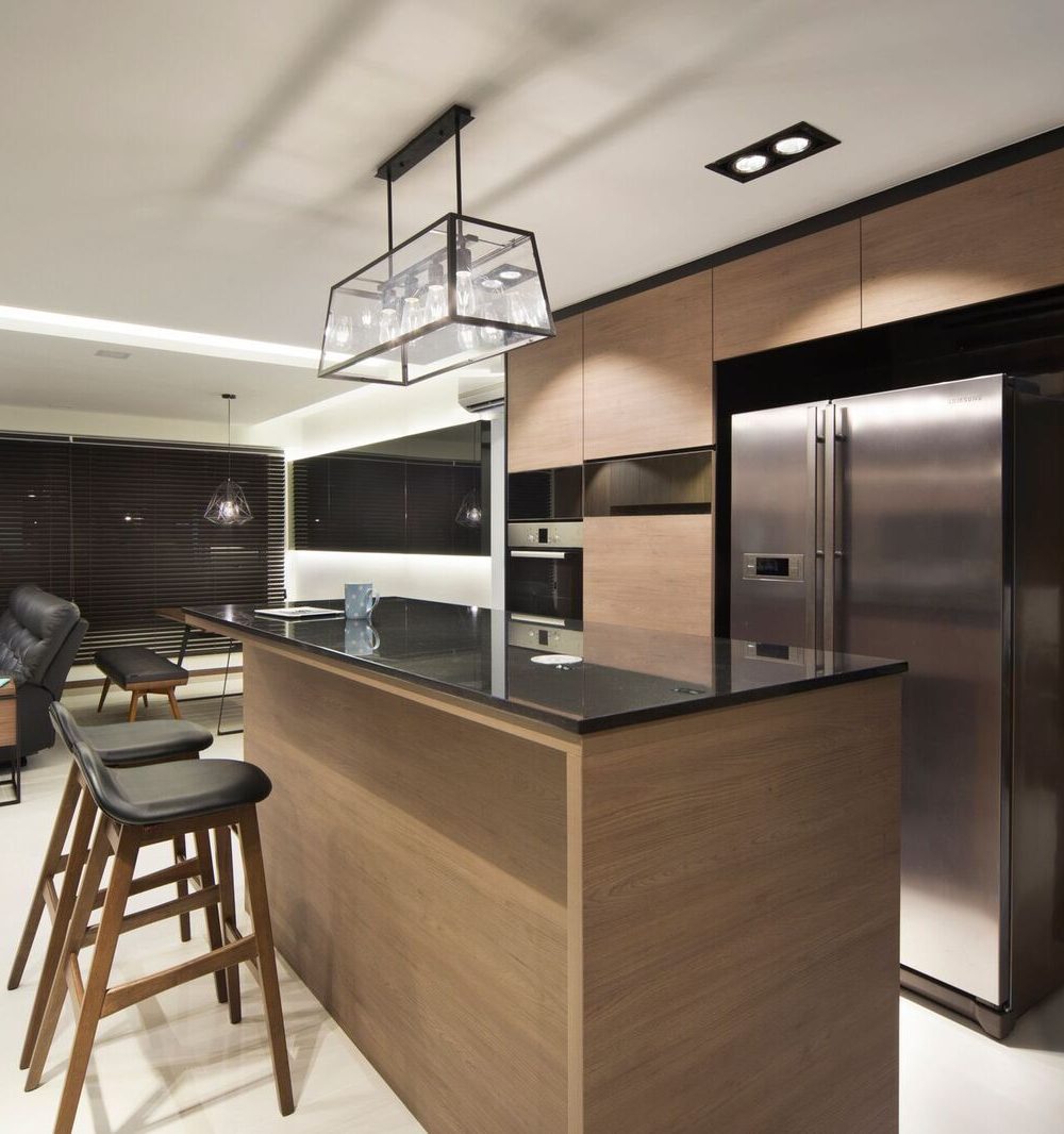 The kitchen island opens directly onto the living room's black leather sofa, keeping the whole space feeling connected.