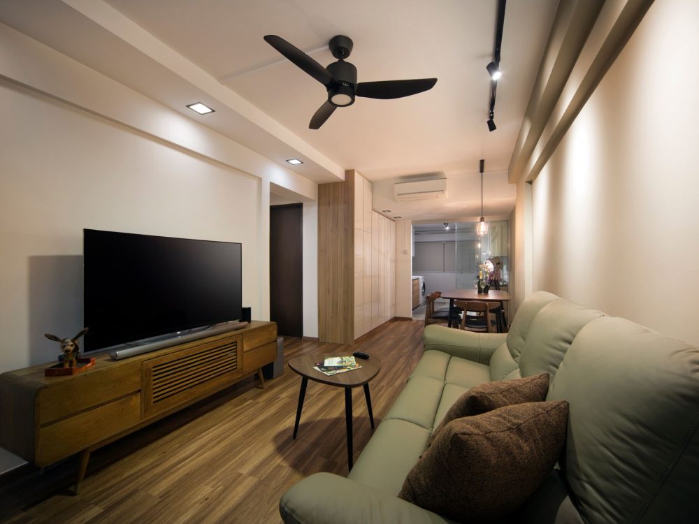 Track lighting and a slim ceiling beam define the living area, with the dining space and utility corridor visible beyond through a run of high-gloss s
