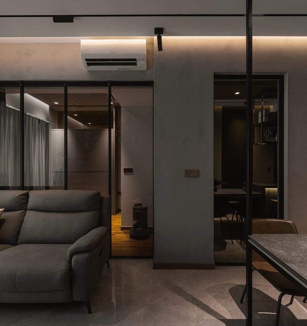 Glass folding doors connect the living room to the bedroom beyond, keeping the compact apartment feeling open and connected.