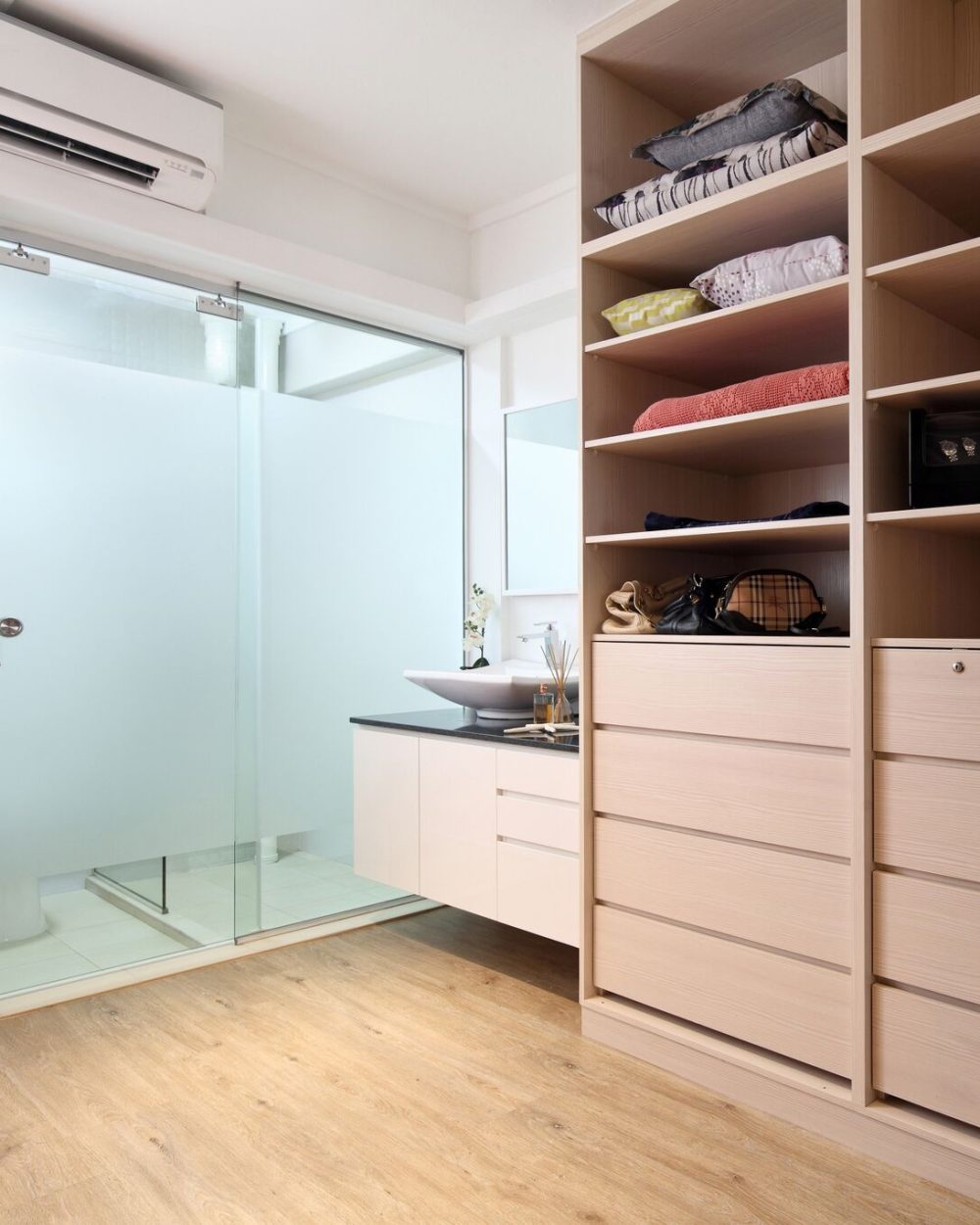 Open timber shelving keeps clothes and accessories visible and organised, leading directly into a sleek black-and-white ensuite bathroom.
