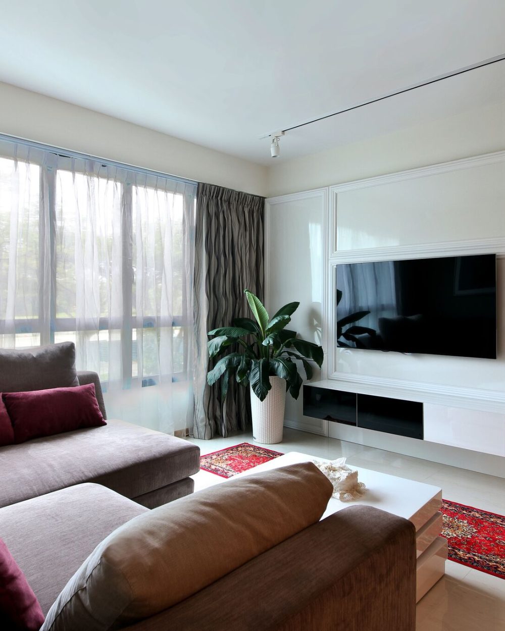 Classical wall panelling wraps the living room's TV feature wall, softened by a plush sectional sofa in grey and plum tones.
