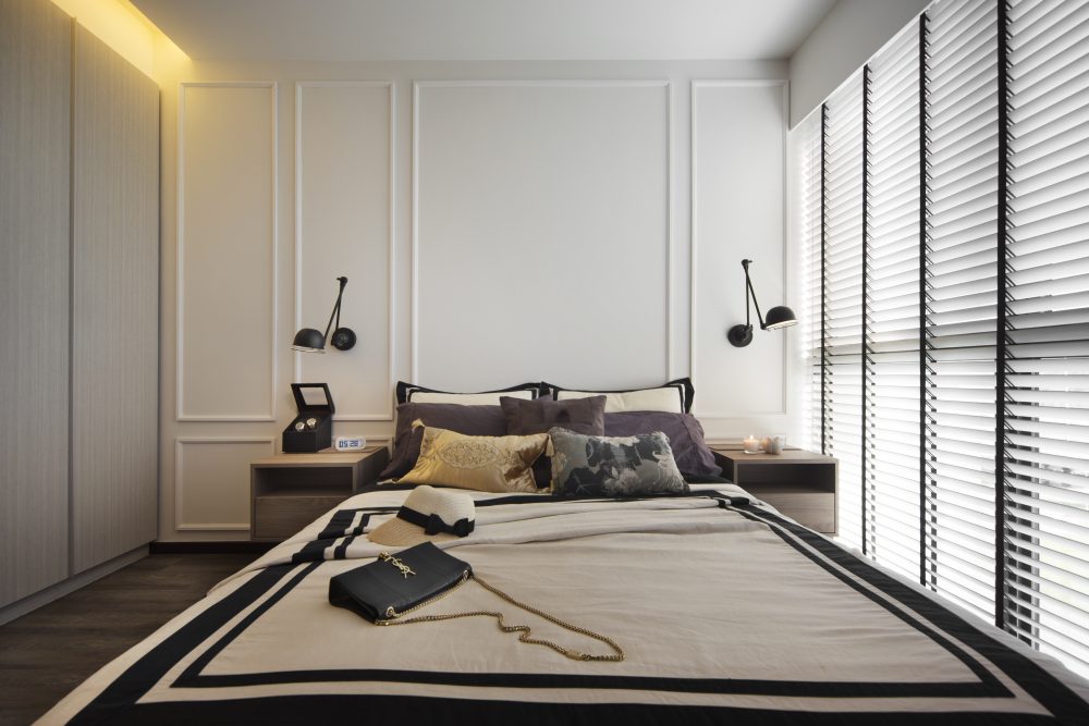 Classic wall panelling and swing-arm sconces frame the headboard wall, finished with layered cushions in charcoal and gold.