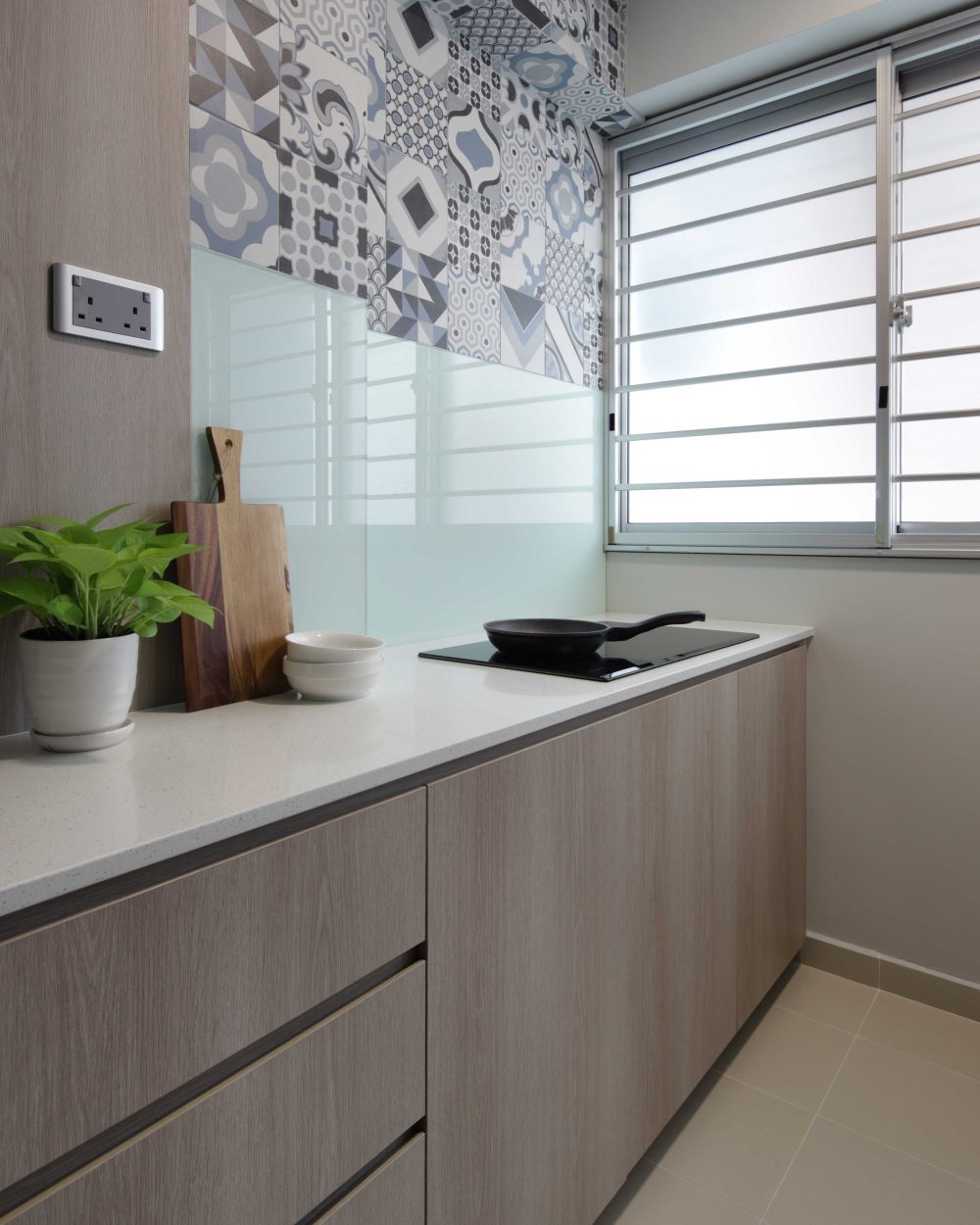 A patchwork of blue-and-white patterned tiles brings personality to the kitchen's backsplash, paired with a glass splashback panel.