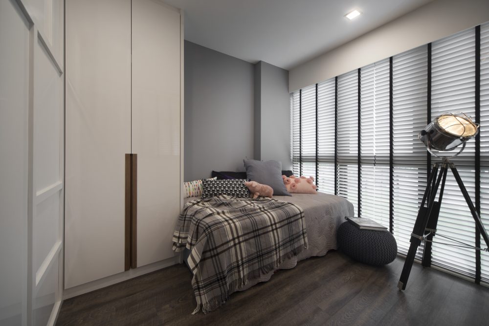 A tripod spotlight lamp and plaid throw give this guest room a relaxed, lived-in character, styled with playful piggy cushions.