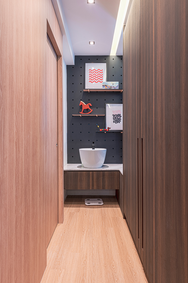 A navy pegboard wall styled with framed art and toys sits beside a freestanding basin, demonstrating a fun, family-friendly bathroom concept.