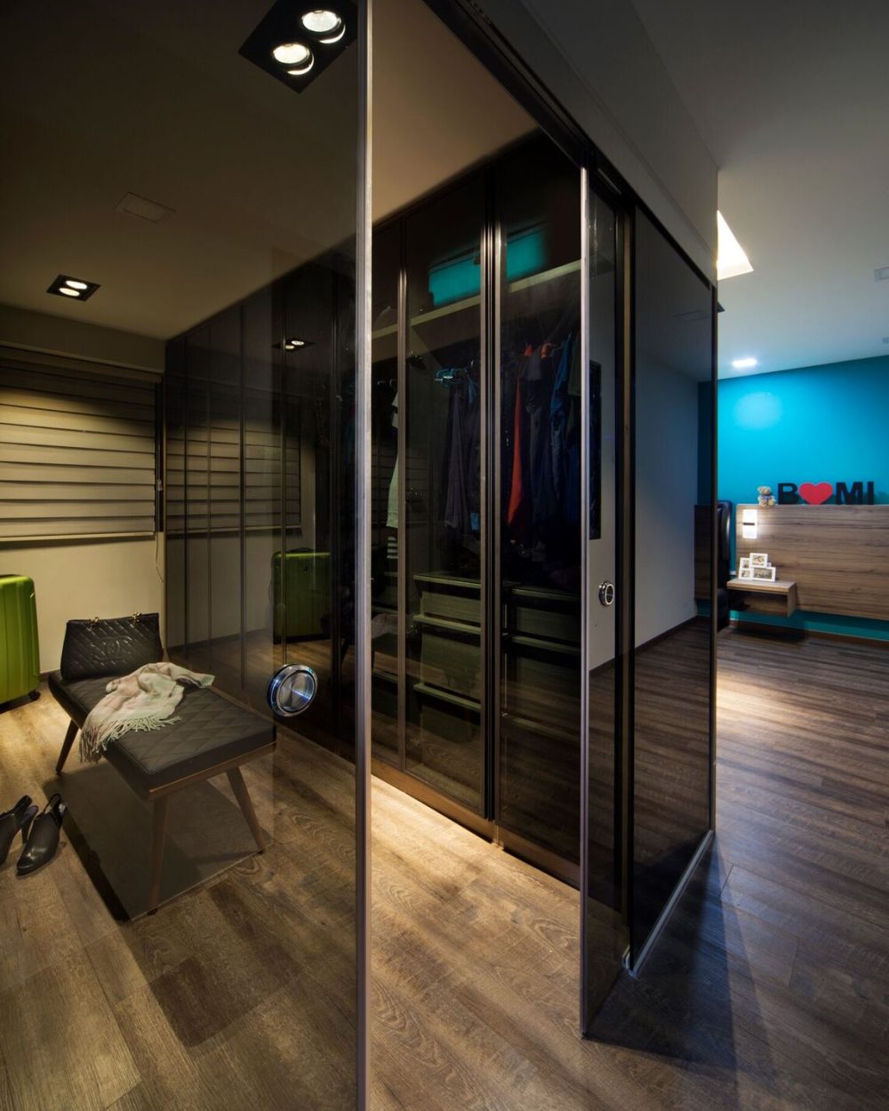 A bright teal feature wall and custom lettering personalise the bedroom, paired with a black tufted leather headboard.