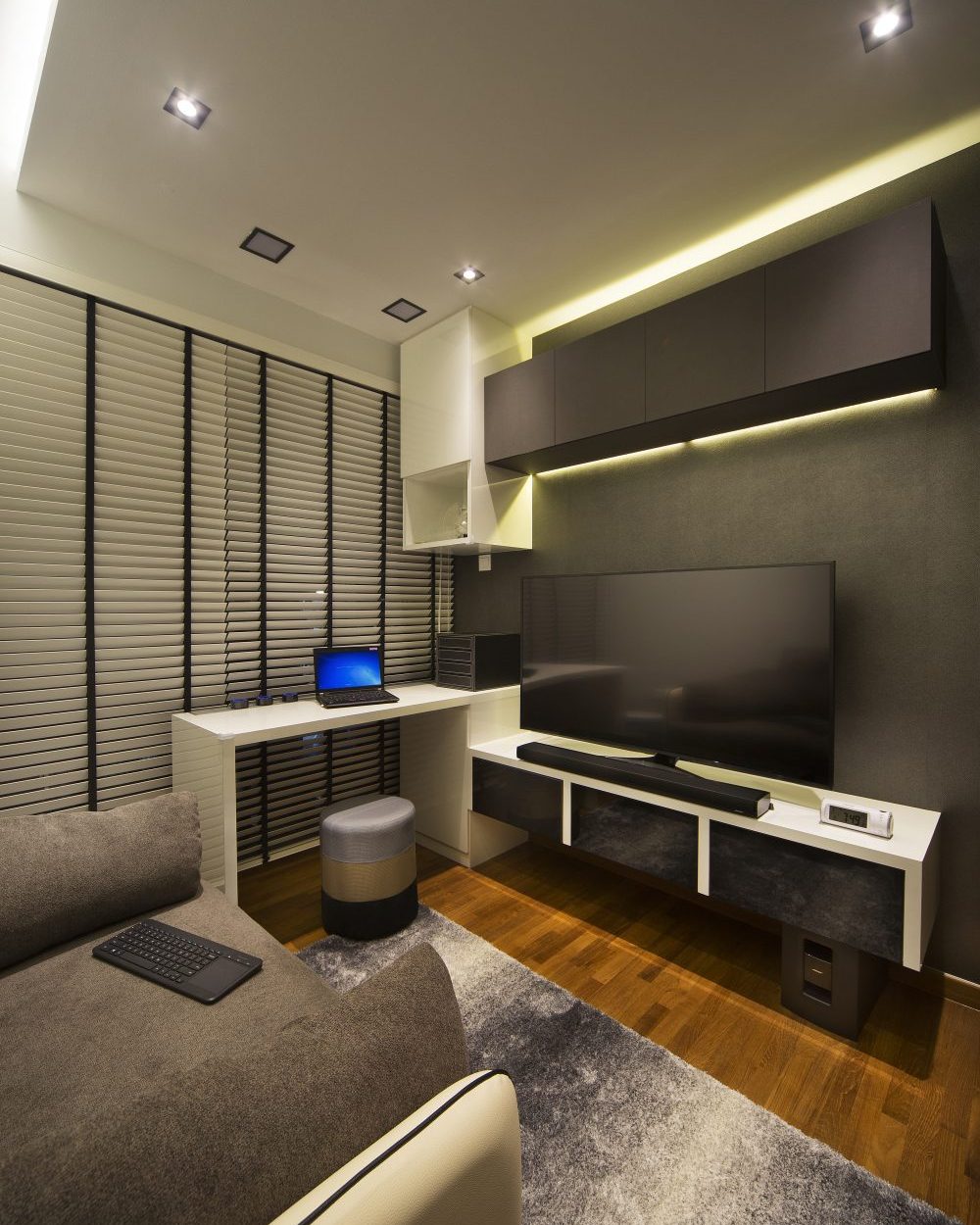 Venetian blinds and a dark feature wall give this study corner a moody, focused character, with a floating desk and wall-mounted TV.