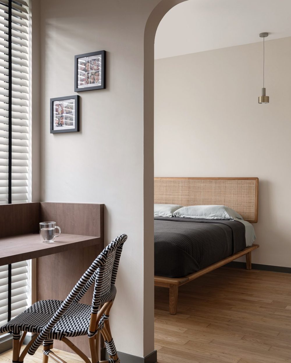 A woven rattan headboard and a single pendant light give the bedroom a relaxed, natural character.