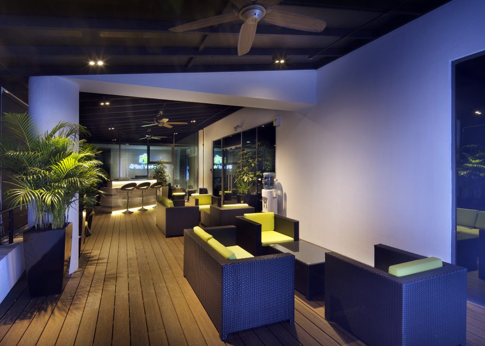 Dark woven rattan armchairs with yellow cushions create an informal lounge area on the terrace, just steps from the bar counter.