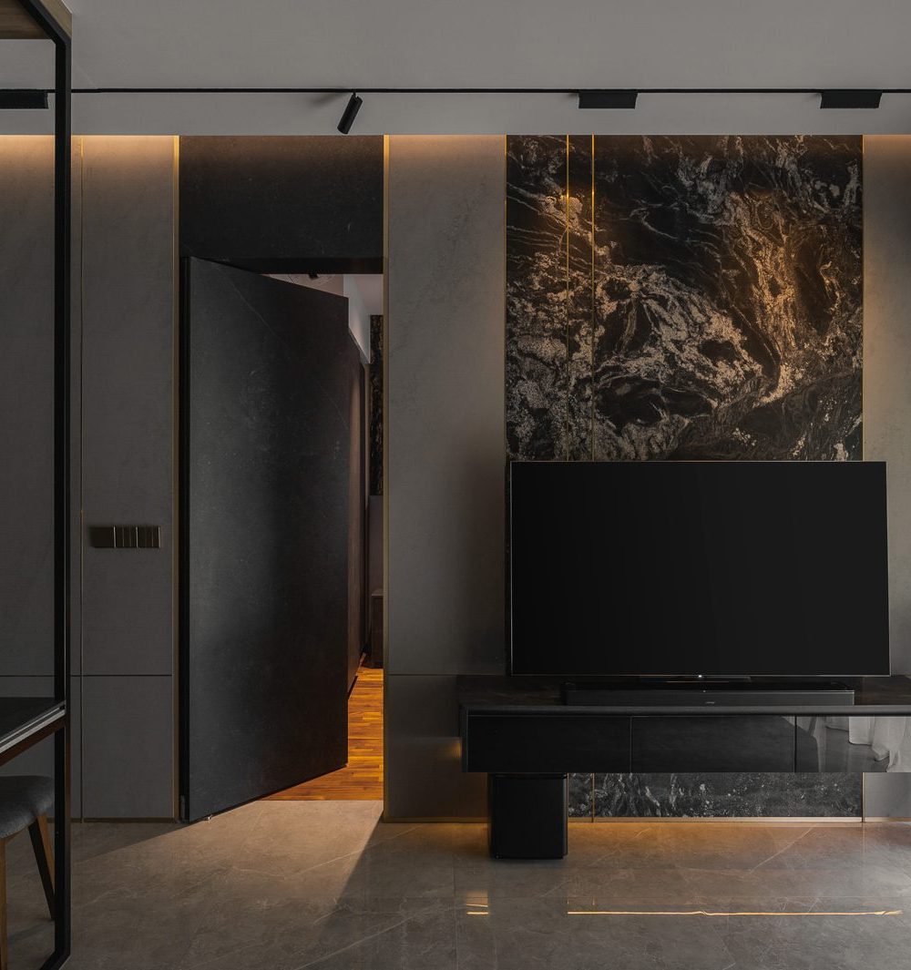 Swung open, the pivot door reveals a warm timber-floored room tucked behind the living room's feature wall.