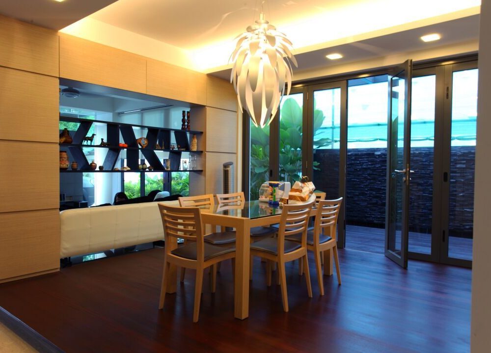 A white sculptural pendant light hangs over the dining table, with bifold doors opening the room directly onto the garden.