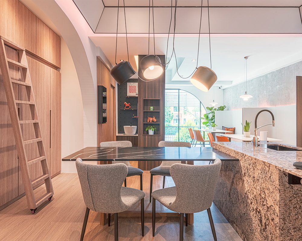 Three black pendant lights and a rolling ladder accompany a second kitchen display, with a pegboard wall showcasing playful design details for a child