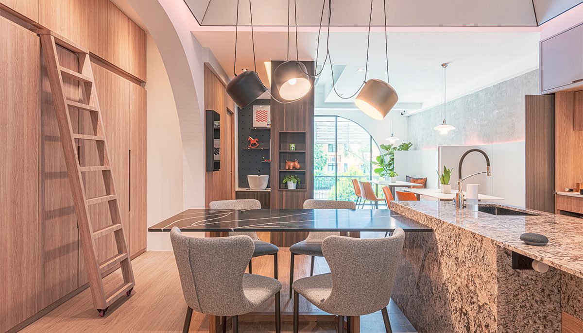 Three black pendant lights and a rolling ladder accompany a second kitchen display, with a pegboard wall showcasing playful design details for a child