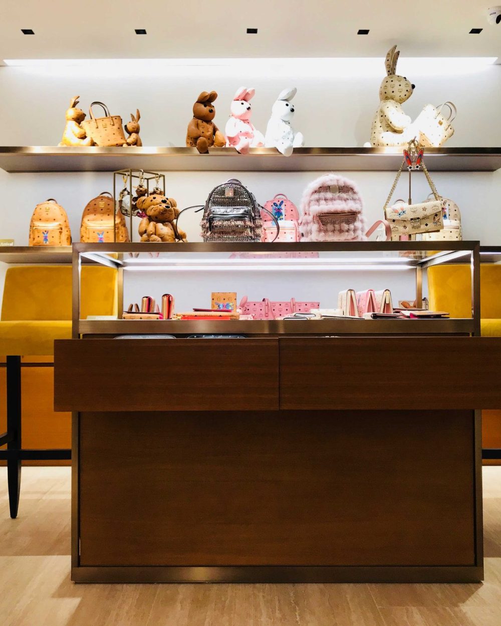 A shelf of MCM's bear and rabbit-shaped bag charms above backpacks and small leather goods.
