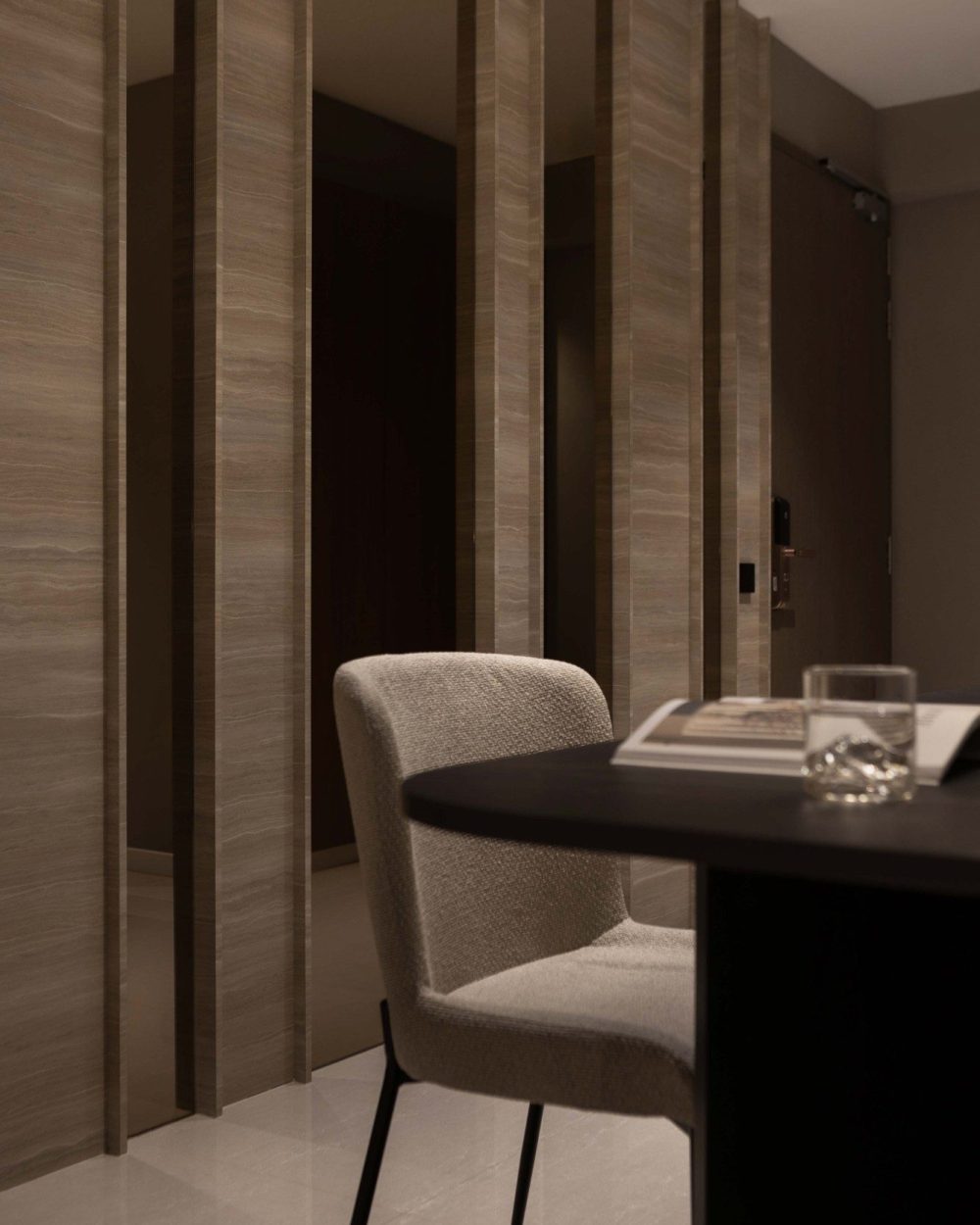 A slatted timber-and-stone screen near the entrance filters the space without closing it off, keeping sightlines open from the dining table to the fro
