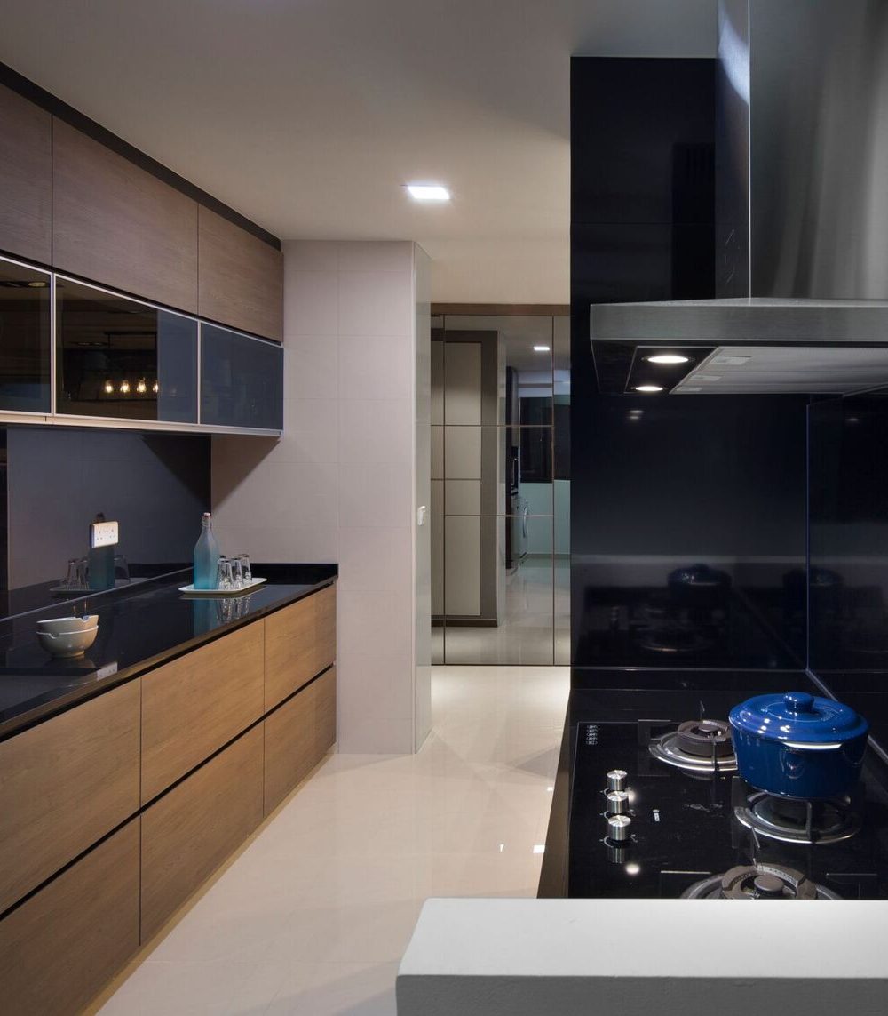 Glossy black glass cabinetry and a matching backsplash frame the cooktop, keeping the kitchen's darker palette concentrated around the cooking zone.