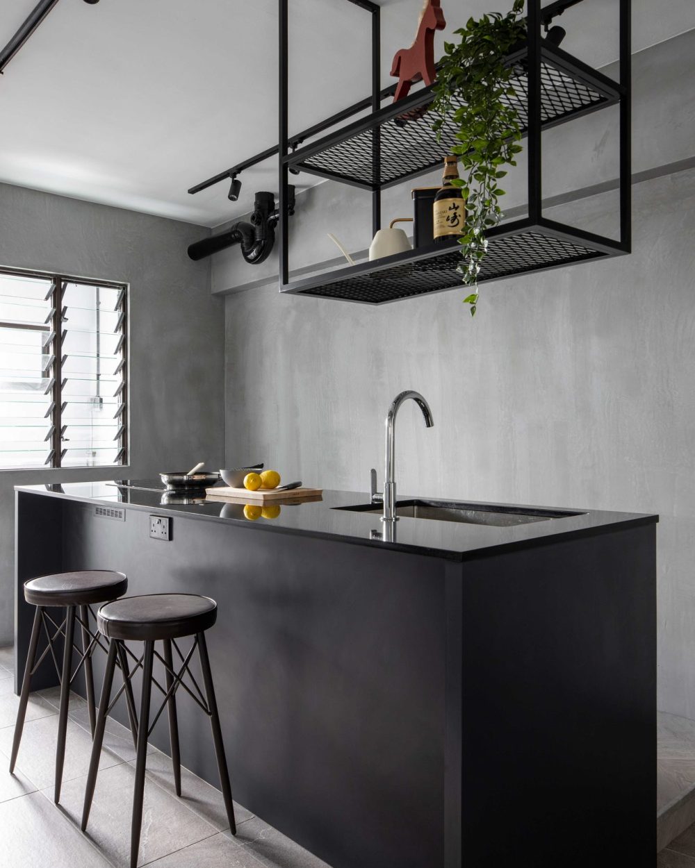 A full-length black island with a marble counter anchors the kitchen, paired with leather-topped bar stools.