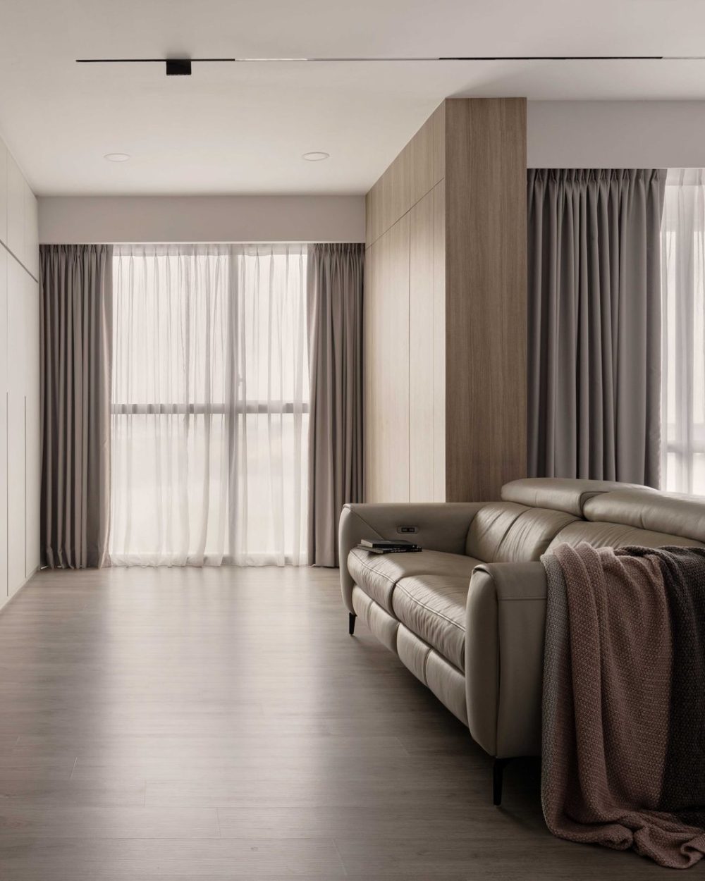 Warm timber columns and grey curtains continue the living room's calm, neutral palette toward the dining area.