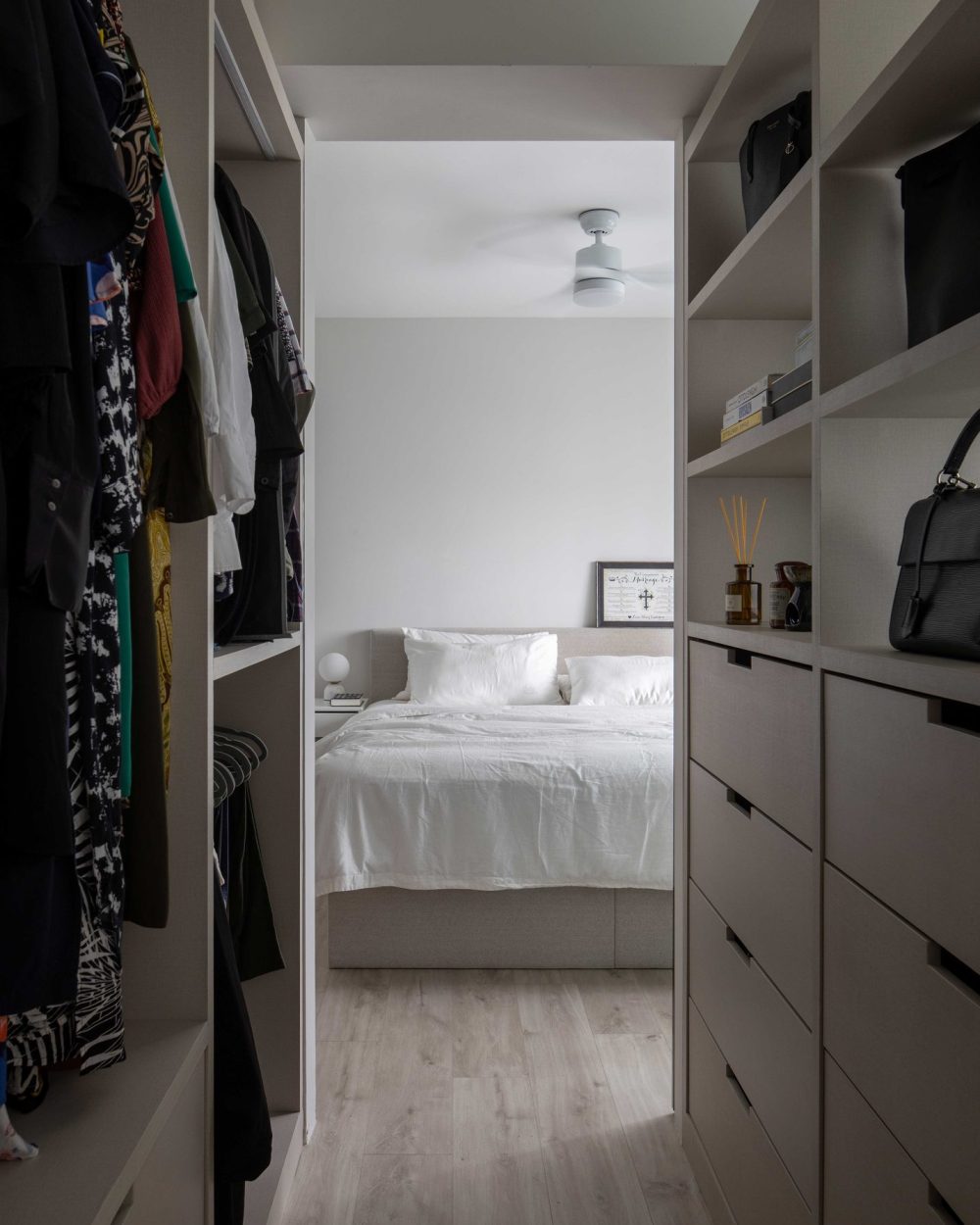 Warm shelf lighting and a reed diffuser bring a hotel-like touch to the wardrobe corridor, just steps from the bed.