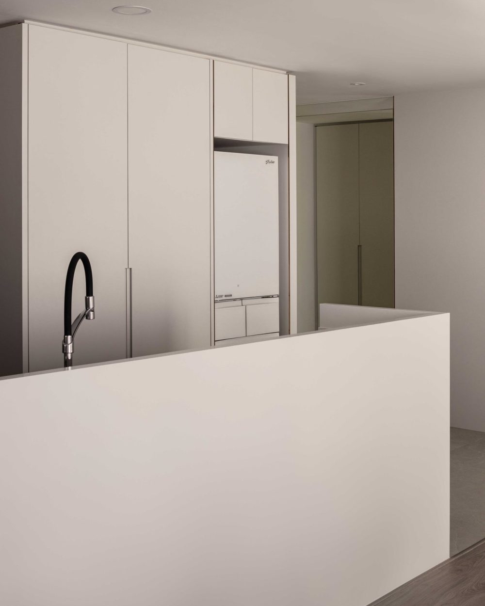 A second view of the fridge column shows how the cabinetry continues unbroken around the corner into the hallway.