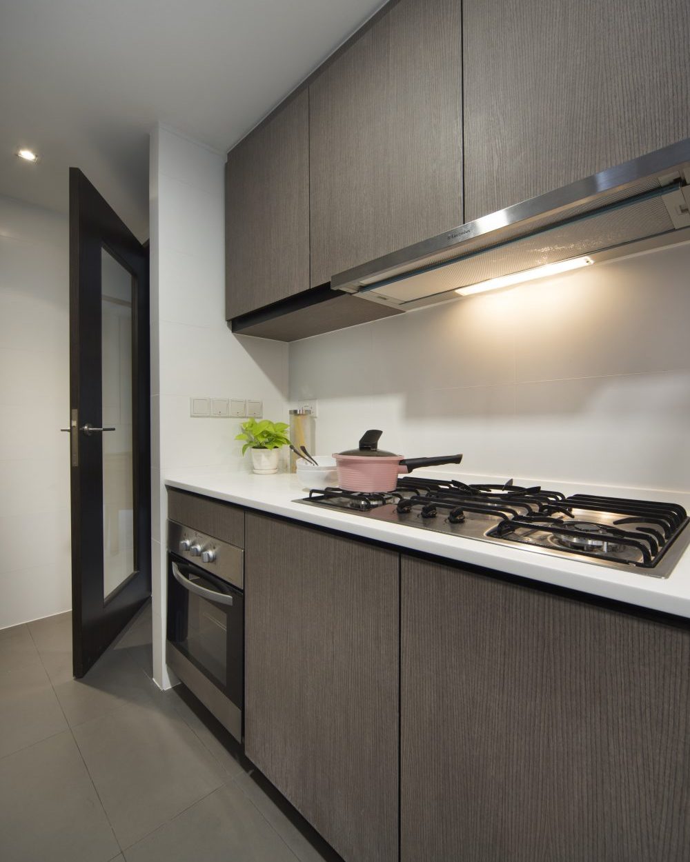 Dark timber cabinetry and a white stone counter keep the kitchen sleek, with a glazed door opening onto the service yard.