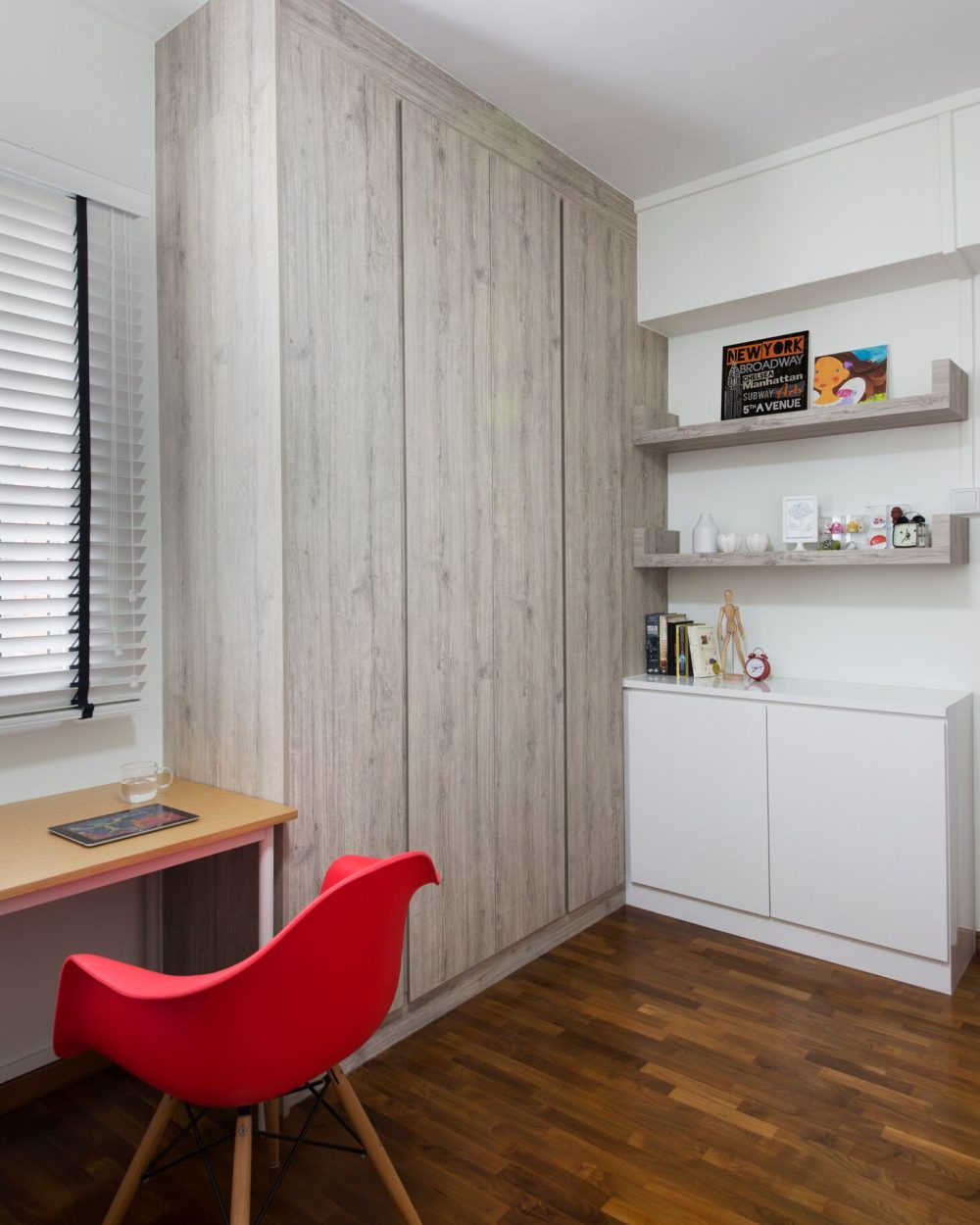 The same wardrobe wall wraps around a small desk positioned by the window, keeping the study corner bright through the day.
