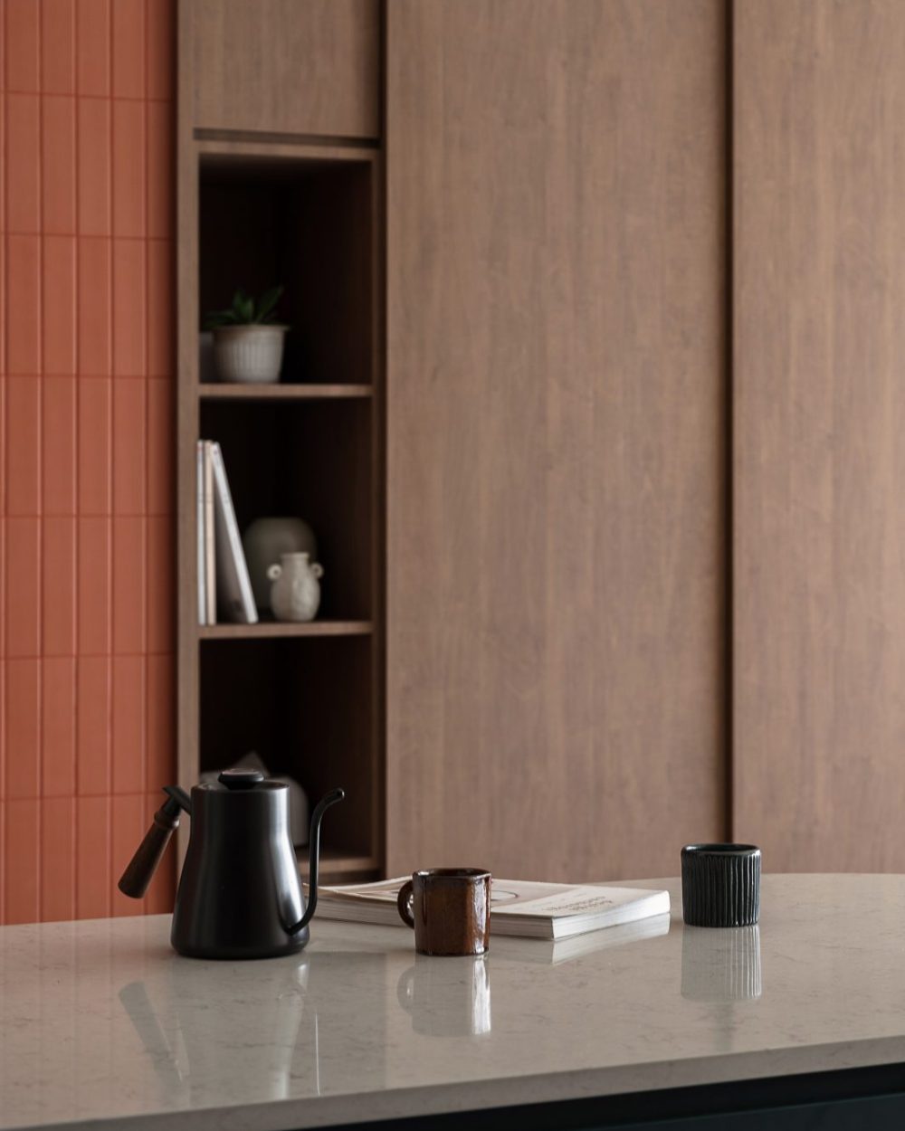 A built-in display niche holds a coffee grinder and potted greenery, tucked beside the kitchen's overhead cabinetry.