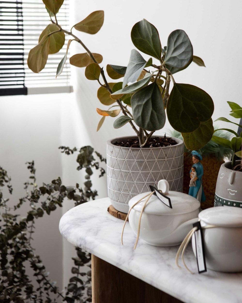 Potted plants and decorative objects are arranged on a marble-topped console, adding texture to the dining corner.